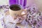 Violet cup of morning coffee or cappuccino and delicate pink, purple, lilac flowers. Mother`s day concept. Cozy