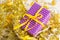 Violet elegant present with yellow ribbon on golden tinsesl and garland