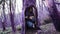 Violet fairytale forest. Funny girl hides in a hollow of the old tree and regards it with the interest and looks out of