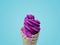 Violet ice cream cone on light blue pastel background.