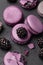 Violet and lilac macarons and blackberries on black concrete background