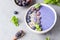 Violet magic smoothie bowl topped with blueberries, blackberries, coconut flakes and seeds.