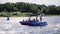 Violet motor boat full of people in it floats in river on sunny summer day.