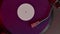 Violet vinyl record spinning on turntable playing disco, punk, grunge, pop music