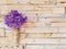 Violet wanda orchid in bamboo vase hanging on wooden plank wall.