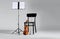 Violin, chair and note stand with music sheets on grey