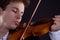 A violinist with closed eyes plays a violin on a dark background