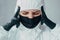 A virologist in a protective suit and medical mask holds his head in black gloves and thinks about how to protect himself from the