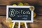 Virtual currency Bitcoin accepted here sign over wooden background with real bitcoins spreading over.