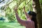 Virtual forest. A young woman among the trees, wearing virtual reality glasses, touches the boles and branches.