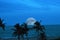 A virtual full moon makes a spectacular entrance to the twilight sky over the tropical ocean below