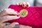 Virtual money golden bitcoin on pink women fabric purse. fingers with red nails on a coin