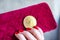 Virtual money golden bitcoin on pink women fabric purse. fingers with red nails on a coin