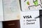 Visa and passport to approved stamped on a document top view in