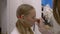 Visagiste applying eyehadow on eyelid of makeup model in makeup studio