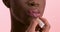 Visagiste applying lip gloss while doing makeup on black transgender model