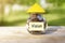 Vision. Glass jar with coins and a yellow triangle from above, on a wooden table, natural background.