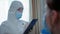 Visit of doctor, female nurse in protective suit mask, glasses and gloves examines young girl in poor health with virus