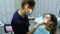 Visit to the dentist. A doctor orthodontist sets up iron braces for a woman with a dental fixator in her mouth