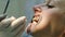 Visit to the dentist. Doctor orthodontist sets up iron braces for a woman with a dental fixator in her mouth close up.