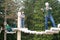 Visitors in adventure park clambering with ropes wear protective