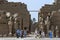 Visitors to the Karnak Temple (Temple of Amun) in Luxor in Egypt walk near a series of ancient statues.