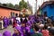 Visitors watching purple robed men carrying a float with Christ and a cross at the procession of San Bartolome de