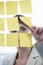 Visualizing her thoughts. a businesswoman arranging sticky notes on a glass wal.