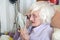 Visually impaired elderly woman reading with magnifying loupe