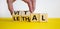 Vital vs lethal symbol. Businessman turns wooden cubes and changes the word `lethal` to `vital`. Beautiful yellow table, white