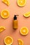 Vitamin C cosmetic lotion pump bottle and orange slices on color background. Citrus beauty product design