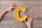 Vitamin C nutrient in food concept. Woman hands holding plate in shape of letter C with orange slices on wooden background. Flat