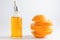 Vitamin C serum in cosmetic bottle with dropper and sliced orange on white background. Organic SPA cosmetics with herbal