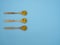 Vitamin D, E or fish oil capsules in wooden spoons on blue background with copy space, top view, flat lay