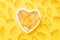 Vitamin D and Omega 3 fish oil capsules supplement in a heart-shaped plate on yellow background. Concept of healthcare