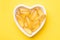 Vitamin D and Omega 3 fish oil capsules supplement in a heart-shaped plate on yellow background. Concept of healthcare