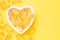 Vitamin D and Omega 3 fish oil capsules supplement in a heart-shaped plate on yellow background. Concept of healthcare