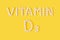 Vitamin D3 pills dropped from bottle on yellow background. Flat lay, top view, free copy space