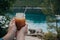 Vitamin orange juice in a glass tube in woman hand on the background of the turquoise sea