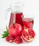 Vitamin pomegranate juice in a glass and a jug near an open juicy pomegranate on a white background.