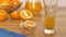 Vitamin-rich orange juice pouring into a transparent glass with slices in a bowl