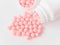 Vitamins. Antiviral drug tablets. Antidepressant. Round pink healthy pills and pill bottle on white background