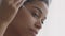 Vitamins for skin. Young african american woman applying serum on her face, making everyday beauty procedures