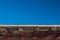 Vivid blue sky over exterior adobe wall, exposed vigas, copy space