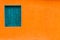 Vivid bright orange colour facade with blue-green window and large empty orange wall texture