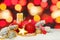 Vivid Christmas composition with red and gold bokeh light, green fir branch, garland, baubles and ribbon on white snow background