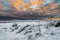 A vivid cloudscape of dramatic evening sky and snow covered half frozen lake with tourists in northern Europe with pine trees