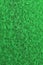 Vivid green vertical background or wallpaper. Rough rugged matt surface. Bright and intense color. A tinted shot of an uneven