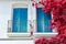 Vivid pink Bougainvillea flowers hanging around balcony with blue doors in Calella de Palafrugel, Spain