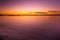 Vivid purple glowing sunset over smooth water.